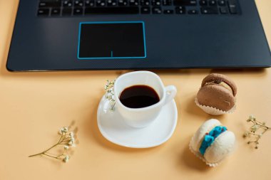 Düz uzanış, üst düzey ofis masası, dizüstü bilgisayarlı çalışma alanı, kahve fincanı ve çiçekli badem kurabiyesi, turuncu arka planda, evden çalışma, uzak çalışma