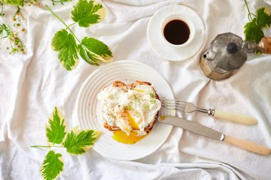 Top view Breakfast on white bed sheets, good morning, toast with poached eggs, coffee, flowers, Hotel room early morning, honeymoon
