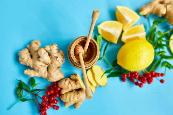 Flat lay of Immune boosting remedy, immunity boosting foods ginger, lemon,  honey,  guelder rose, mint on blue background Top view, copy spac
