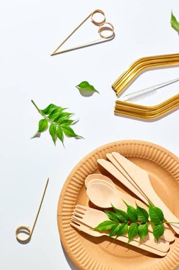 Çevre dostu sofra takımı, yeniden kullanılabilir tek kullanımlık tabaklar, bardaklar, paslanmaz çelik pipetler ve beyaz arka planda sert gölgeli temizlik fırçası. Biyolojik çözünebilir el işi çanakları, geri dönüşüm konsepti