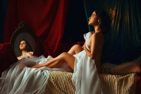 Девушка в красных, зеленых и белых тканях с зеркалом