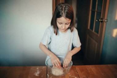 Bir kız mutfakta turta pişiriyor.