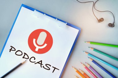 Masasında kalem ve kulaklıkla beyaz kağıda yazılmış podcast.