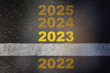 2022 'den 2025' e kadar beyaz çizgili asfalt yol yüzeyinde göze çarpıyor. Mutluluğa yeni yıl konsepti başlıyor ve taşınmaya devam ediyoruz.
