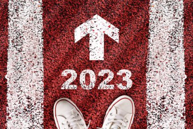 New year 2023 and white arrow sign written on red road surface with marking lines. start to recovery concept and 