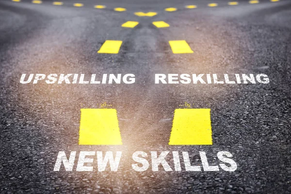 Self development for wellbeing concept and changing skill demand idea. New skills, reskilling and upskilling written on asphalt road
