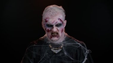 Cadılar Bayramı kostümlü uğursuz adam yaralı suratlı çılgın zombi korkutmaya çalışıyor.