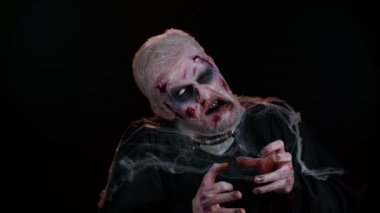 Korkunç korkunç Cadılar Bayramı zombi makyajlı uğursuz adam kasılmalarla yüzünü korkutmaya çalışıyor.