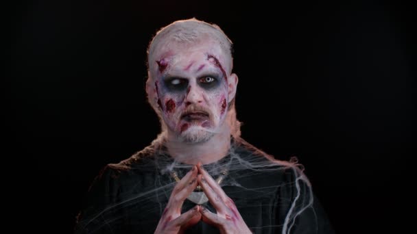 Frightening man with Halloween zombie bloody wounded makeup, trying to scare, praying, horror theme — Stock Video