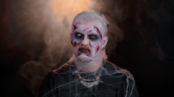 Înfricoșător rănit de Halloween zombie monstru strigoi face fețe, se uită la aparat de fotografiat și zâmbește teribil — Videoclip de stoc