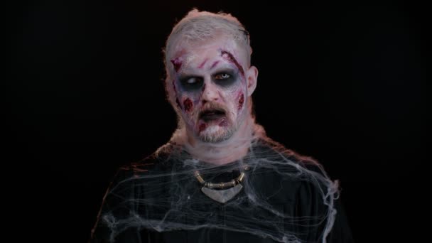 Ondskefull man med fruktansvärd skrämmande Halloween död zombie makeup i kostym tittar olycksbådande på kameran — Stockvideo