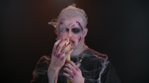 Gruseliger Mann mit Halloween-Zombie zaubert blutigen Schminkzauber über Kerzen, Voodoo-Rituale — Stockvideo