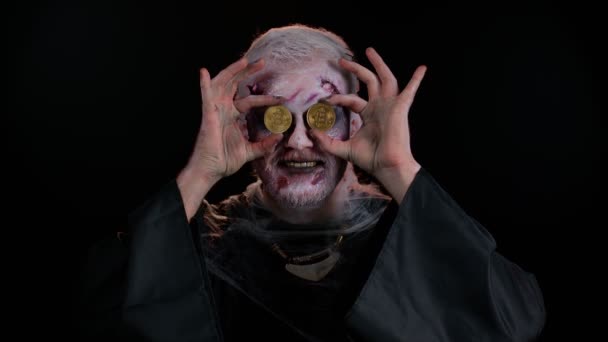 Straszny człowiek z krwawymi bliznami na twarzy, zombie Halloween pokazuje złote bitcoiny wydobycia przyszłej technologii — Wideo stockowe
