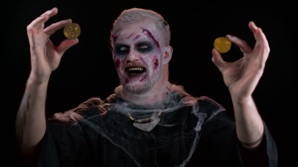 Zombie muž s make-upem s falešnými ranami jizvy ukazující zlaté bitcoiny, těžba btc kryptoměna — Stock video