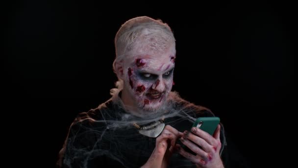 Glad glada olycksbådande man Halloween zombie använda smartphone firar lotteri vinna, framgång lycka till — Stockvideo
