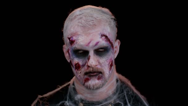 Sinister man in costume of Halloween crazy zombie with bloody wounded scars face trying to scare — Stock Video