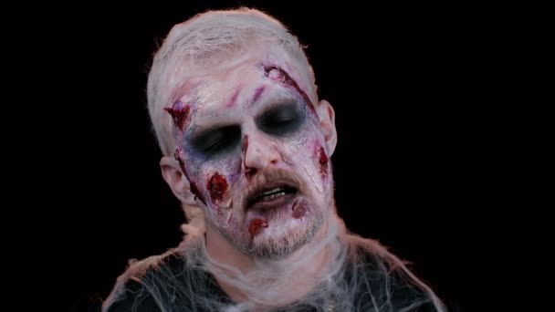 Зомбі чоловік з макіяжем з підробленими ранами шрами дивиться на камеру і кричить, намагаючись налякати — стокове відео