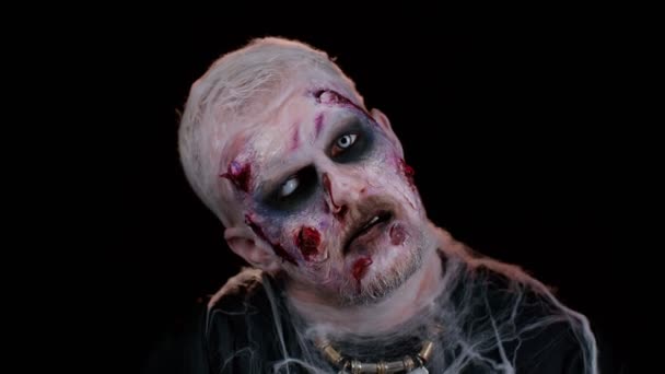 Зловещий человек с ужасной страшной зомби-макияж Хэллоуина в конвульсиях делает лица, пытаясь напугать — стоковое видео
