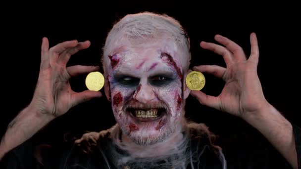 Homem zumbi com maquiagem com feridas falsas cicatrizes mostrando bitcoins dourados, mineração btc criptomoeda — Vídeo de Stock