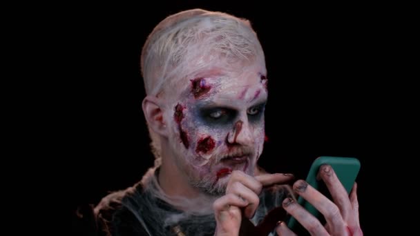 Szczęśliwy podekscytowany złowieszczy człowiek Halloween zombie używać smartfona świętując wygraną na loterii, szczęście sukcesu — Wideo stockowe