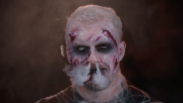 Omul sinistru Zombie de Halloween cu fata sângeroasă suflă fum din nas și gură, făcând sărutul musca de aer — Videoclip de stoc