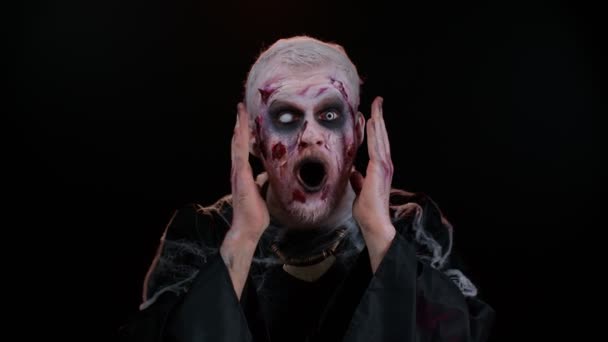 Страшний чоловік Хеллоуїн зомбі піднімає руки в несподіваному вигляді шокований раптовою перемогою — стокове відео