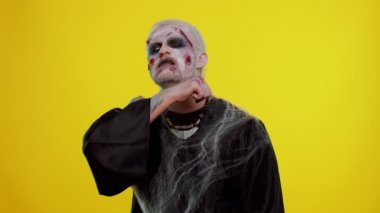 Şeytani bir adam Cadılar Bayramı zombisi öldürme hareketi göstererek korkutmaya çalışıyor.