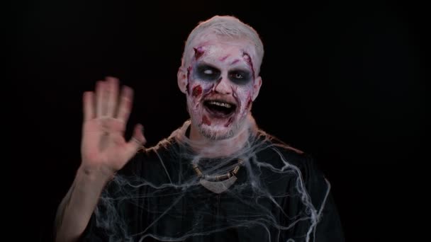 Моторошний Хеллоуїн зомбі чоловік посміхається дружніми махаючи руками жестикулюючи привіт або прощання, вітаючи — стокове відео