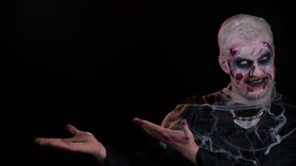 Korkunç yaralı cadılar bayramı zombisi ölümsüz adam boş alanda baş parmak gösteriyor ve solu işaret ediyor. — Stok video