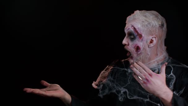 Хэллоуин зомби показывая большие пальцы вверх, указывая пустое место рекламной области для коммерческого логотипа текста — стоковое видео