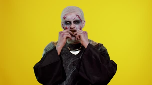 Przerażający człowiek z krwawymi bliznami na twarzy, Halloween zombie wymiotuje złotymi bitcoinami wydobywającymi przyszłą technologię — Wideo stockowe