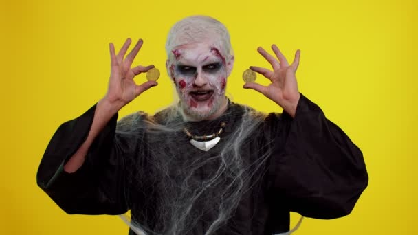 Straszny człowiek z krwawymi bliznami na twarzy, zombie Halloween pokazuje złote bitcoiny wydobycia przyszłej technologii — Wideo stockowe