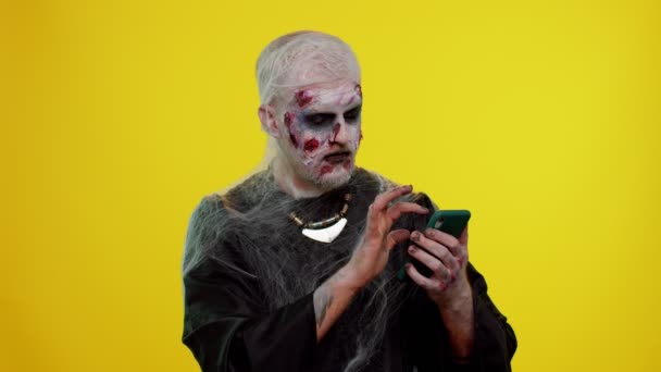 Szczęśliwy podekscytowany złowieszczy człowiek Halloween zombie używać smartfona świętując wygraną na loterii, szczęście sukcesu — Wideo stockowe