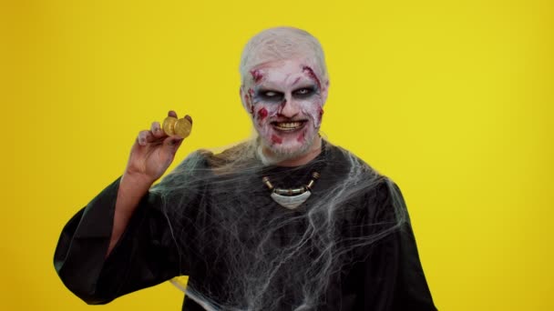 Homem assustador com cicatrizes sangrentas rosto, Halloween zumbi mostrando bitcoins dourados mineração tecnologia futura — Vídeo de Stock