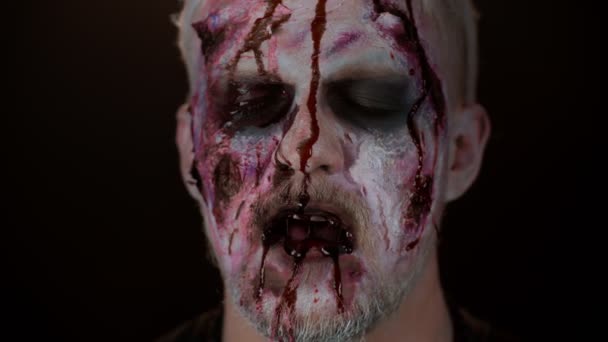 Primer plano del hombre siniestro con horrible espeluznante maquillaje zombie de Halloween fluye sangre y gotea en la cara — Vídeos de Stock