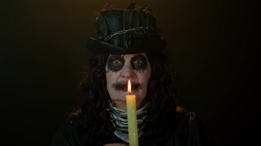 Korkunç korkunç cadılar bayramı cadı makyajlı yaşlı kadın elinde mum tutuyor.