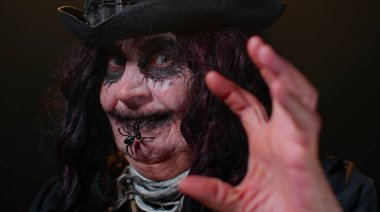 Korkunç korkunç olgun kadın büyükanne Cadılar Bayramı stili cadı makyajıyla korkunç suratlar yapıyor.