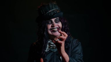 Korkunç korkunç Cadılar Bayramı cadı makyajlı yaşlı kadın kameraya uğursuz bakıyor.