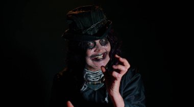 Cadılar Bayramı cadı makyajlı ürkütücü yaşlı nine kameraya bakıyor, korkutmaya çalışıyor, yüz ifadeleri takınıyor