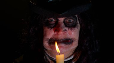 Korkunç Cadılar Bayramı cadı makyajlı uğursuz kadın mumla büyü ayinleri yapıyor.