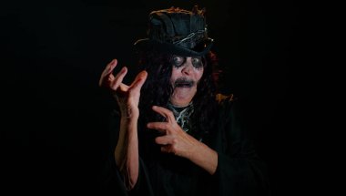 Cadılar Bayramı makyajlı, korkutucu yaşlı kadın müzik dinliyor, gülümsüyor, disko müziği eşliğinde dans ediyor.