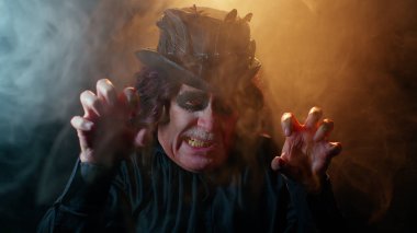 Korkunç korkunç Cadılar Bayramı cadı makyajlı uğursuz adam yüzünü korkutmaya çalışıyor.