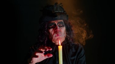 Korkunç cadılar bayramı cadı makyajlı uğursuz adam mumla büyü ayinleri yapıyor.