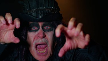 Korkunç korkunç Cadılar Bayramı cadı makyajlı uğursuz adam yüzünü korkutmaya çalışıyor.