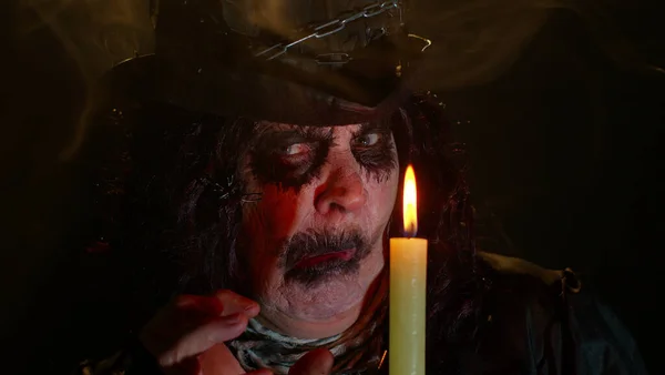 Gruselige Seniorin mit Halloween-Hexenschminke schaut Kerze an, zaubert, hex, wiz — Stockfoto