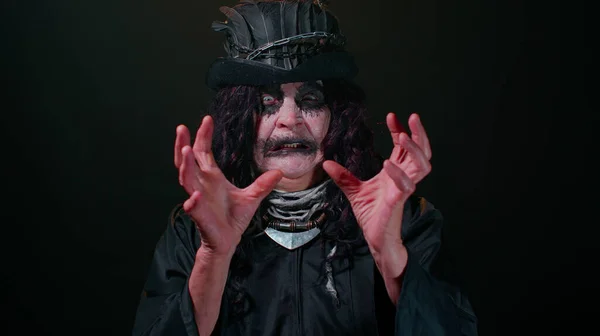Gruselige Oma mit Halloween-Hexen-Make-up, die in die Kamera schaut, versucht zu erschrecken, Gesichtsausdrücke — Stockfoto