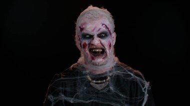 Yara izi ve lensleri olan zombi adam kameraya bakıp dişlerini gıcırdatarak korkutmaya çalışıyor.
