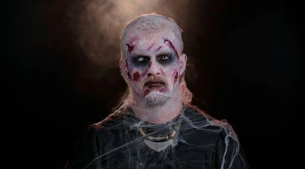 Ondskefulla djävul man med skrämmande Halloween död zombie makeup i kostym gör ansikten, försöker skrämma — Stockfoto