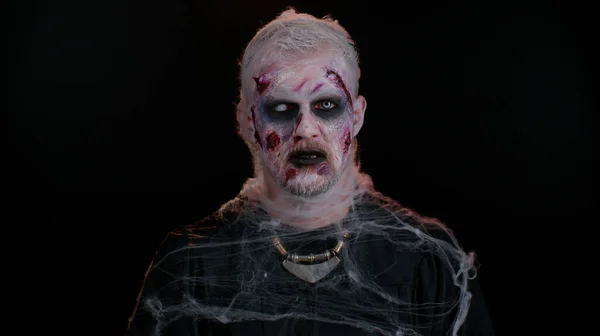 Zombie hombre con cicatrices heridas y lentes de contacto mirando la cámara hace clic en sus dientes tratando de asustar —  Fotos de Stock