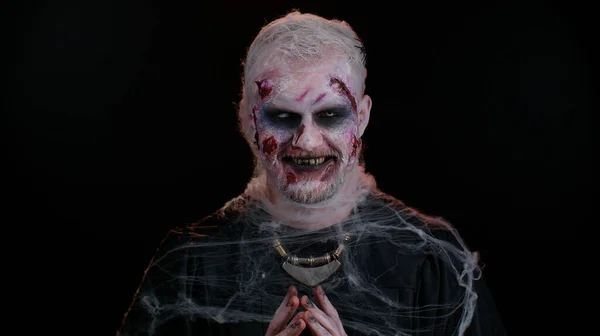 Приголомшливий зловісний чоловік в костюмі зомбі Хеллоуїна з кривавими пораненими шрами стикається намагаючись налякати — стокове фото